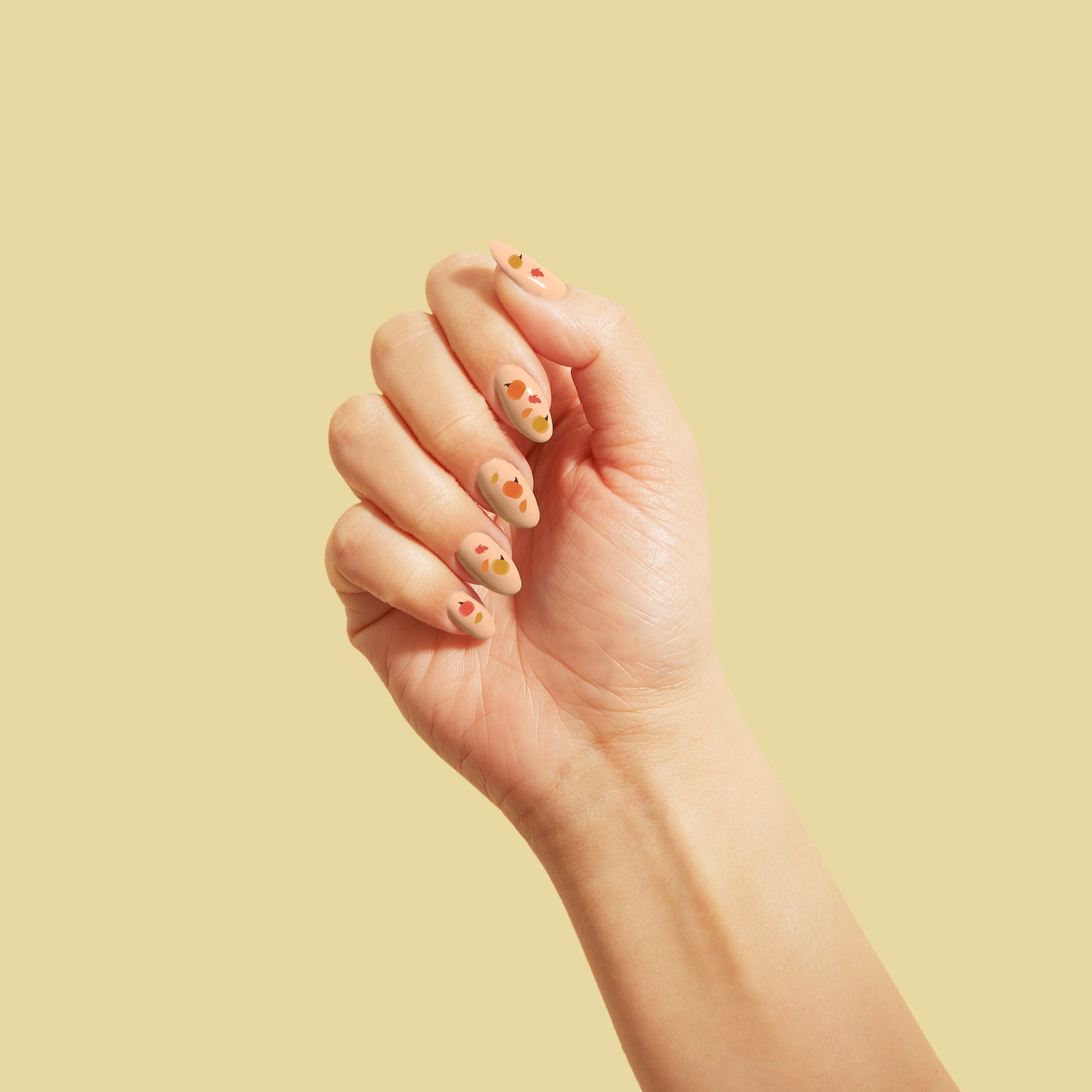Pumpkin Pie Nail Stickers on a manicured hand, yellow background
